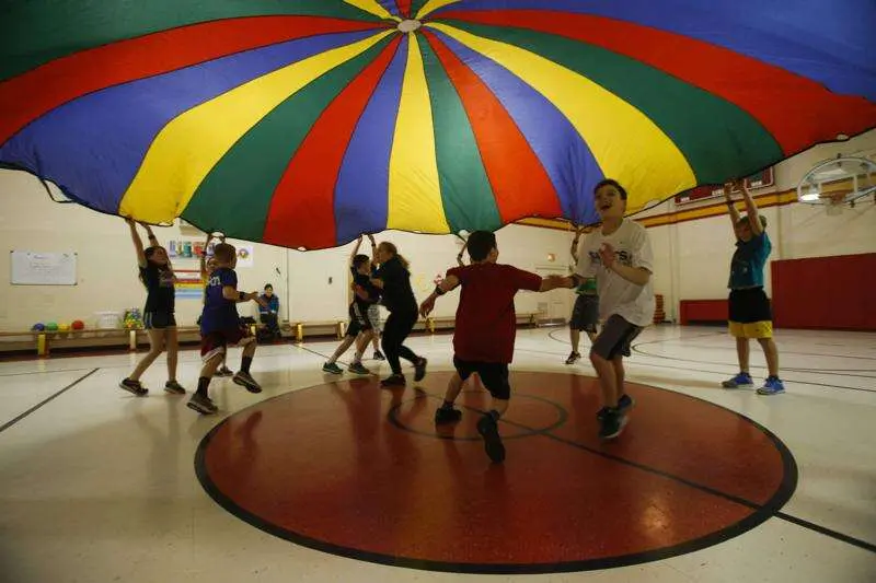 PE students playing under parachute with heart rate monitors on