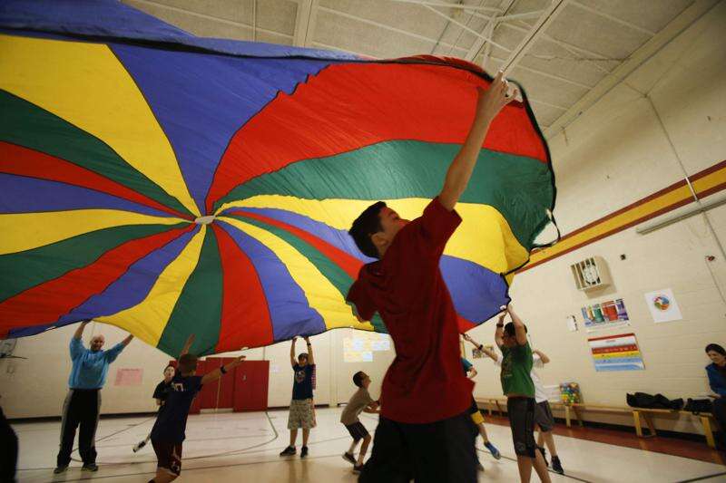 PE students moving parachute up and down while wearing monitors