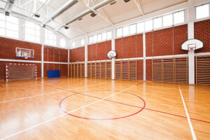 "Brand new school gymnasium, with basketball backboards, and goals"